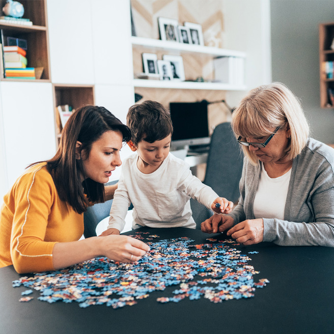Familie sitzt am Tisch und puzzelt