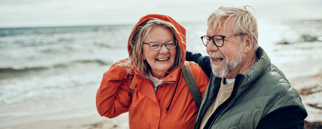 Älteres Ehepaar in Regenjacken am Strand