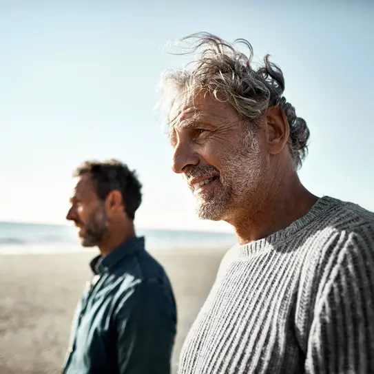 Zwei Männer gehen am Strand spazieren.