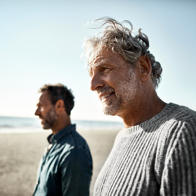 Zwei Männer gehen am Strand spazieren.