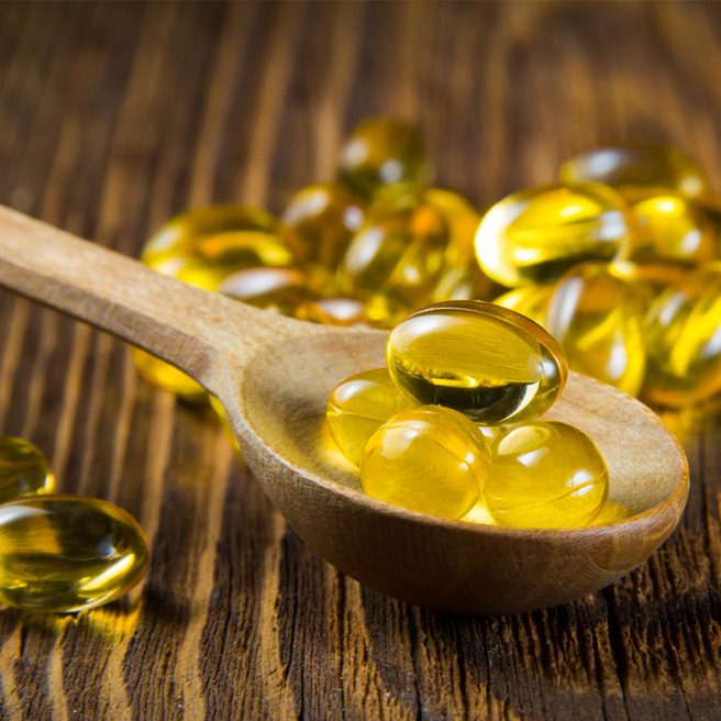 Omega-3 Kapseln auf Holzlöffel