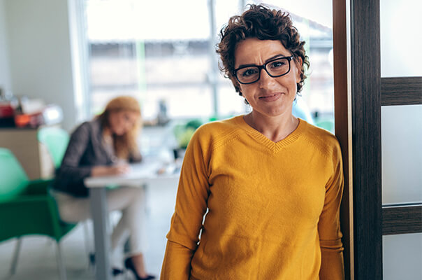 Frau mit Brille lehnt an Tür