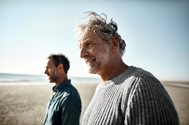 Zwei Männer gehen am Strand spazieren.